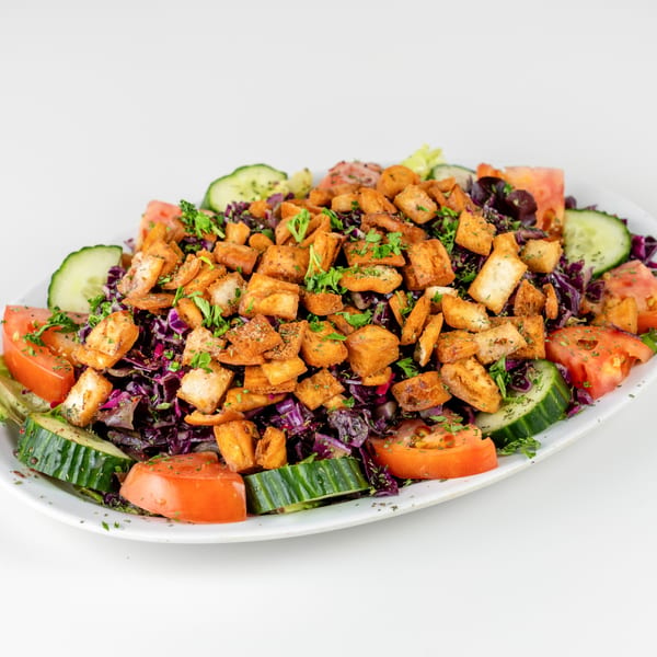 A vibrant Falafel Hut Fattoush salad with red cabbage, tomatoes, cucumbers, and crispy pita bread.
