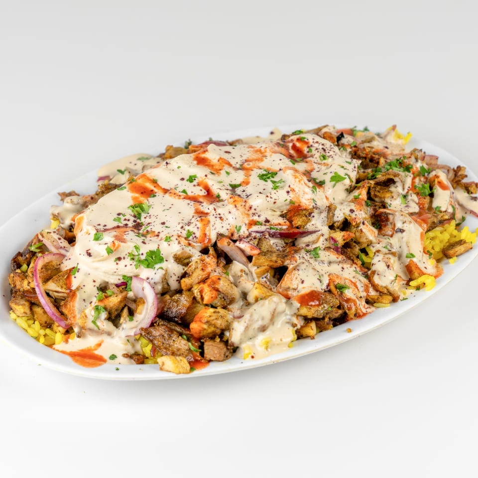 Falafel Hut's chicken and beef shawarma platter with rice, red onions, tahini, and hot sauce.
